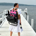 ParkIt Chair with the signature Nora fleming pattern with a cooler and drink holder nora is wearing it with the backpack straps on the dock at the lake