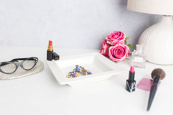 red lipstick and square napkin holder with pink roses and reading glasses