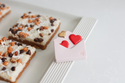 love notes mini with hearts coming out of an envelope on a melamine tray with brownies