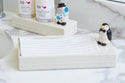 penguin mini on a napkin holder with a snowman mini on a soap and lotion holder in the background