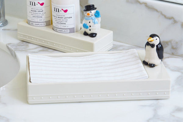 penguin mini on a napkin holder with a snowman mini on a soap and lotion holder in the background