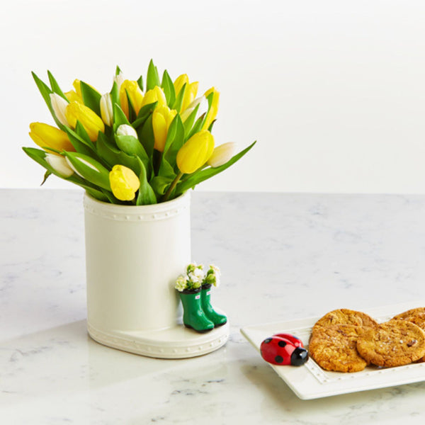 rain boot and lady bug minis on cracker tray and utensil crock filled with yellow tulips