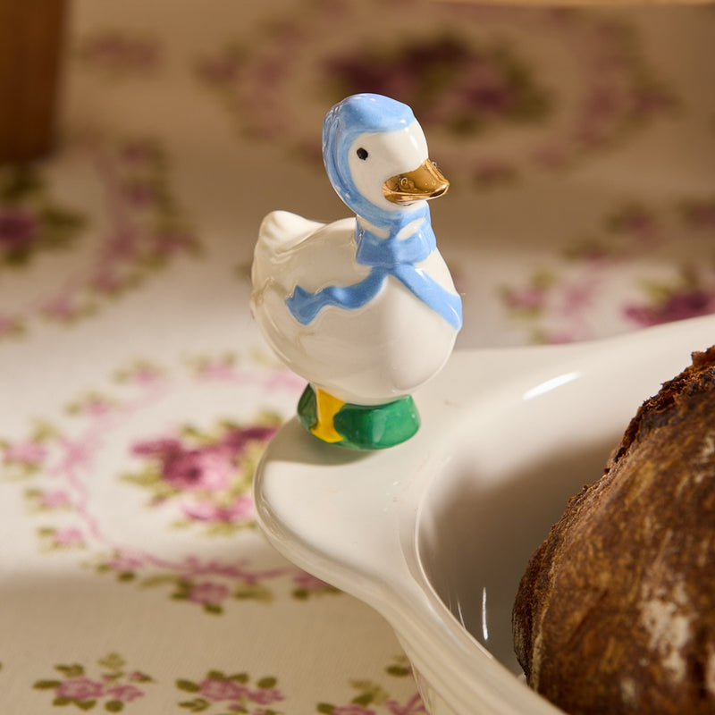Decorative duck figurine with a blue hood on a floral-patterned surface