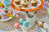 robbin's egg blue mini on a cutie container base. a round platter on a riser with carrot cake cupcakes and an easter basket mini. round bowl with a carrot mini on top of it and filled with decorative eggs.