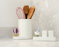 White container with kitchen utensils on a light surface