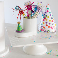 celebration hat on a white cutie container filled with noise makers for a party!