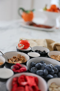 Assorted fruits and granola in small bowls on a table.