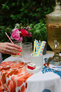 Outdoor setting with a tablecloth, glasses, and decorative elements.