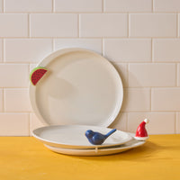 Two ceramic plates with decorative elements on a wooden surface against a tiled wall.