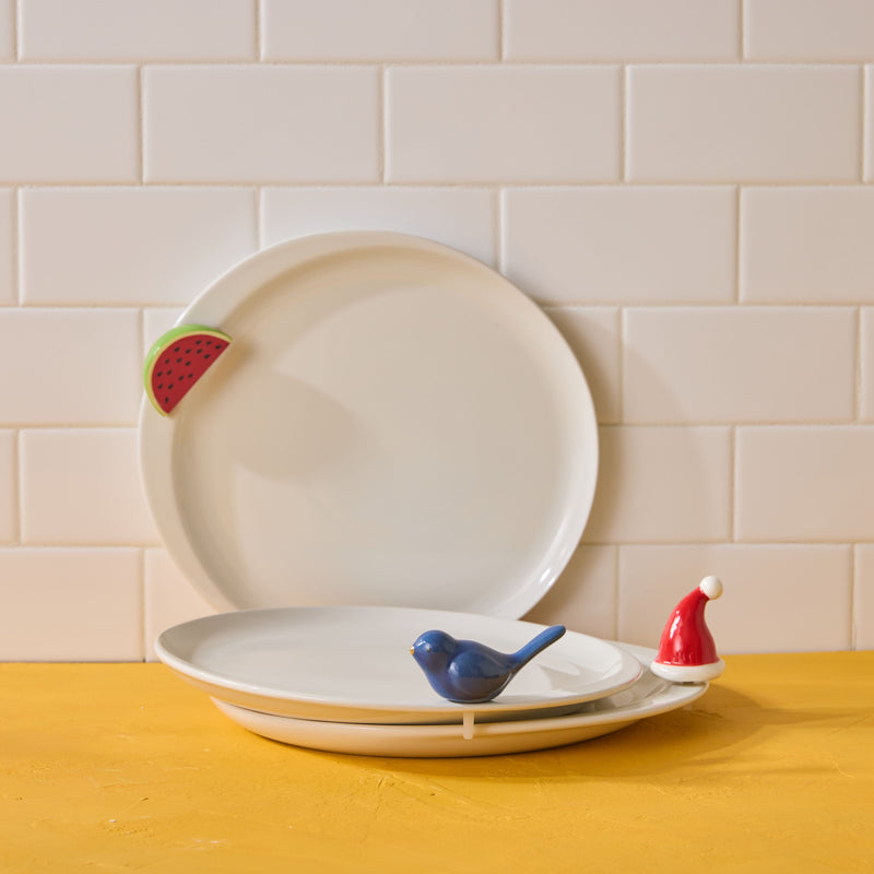 Two ceramic plates with decorative elements on a wooden surface against a tiled wall.