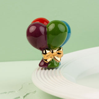Colorful balloon-shaped mini with a gold bow on a white surface.