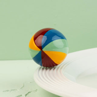 Colorful beachball on a white surface with a green background