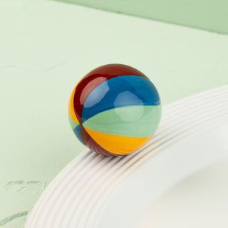 Colorful beachball on a white surface with a green background