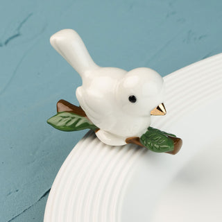 White ceramic bird mini on a branch with a blue background