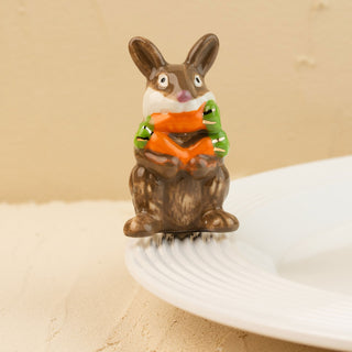 Decorative rabbit mini holding a carrot on a beige background