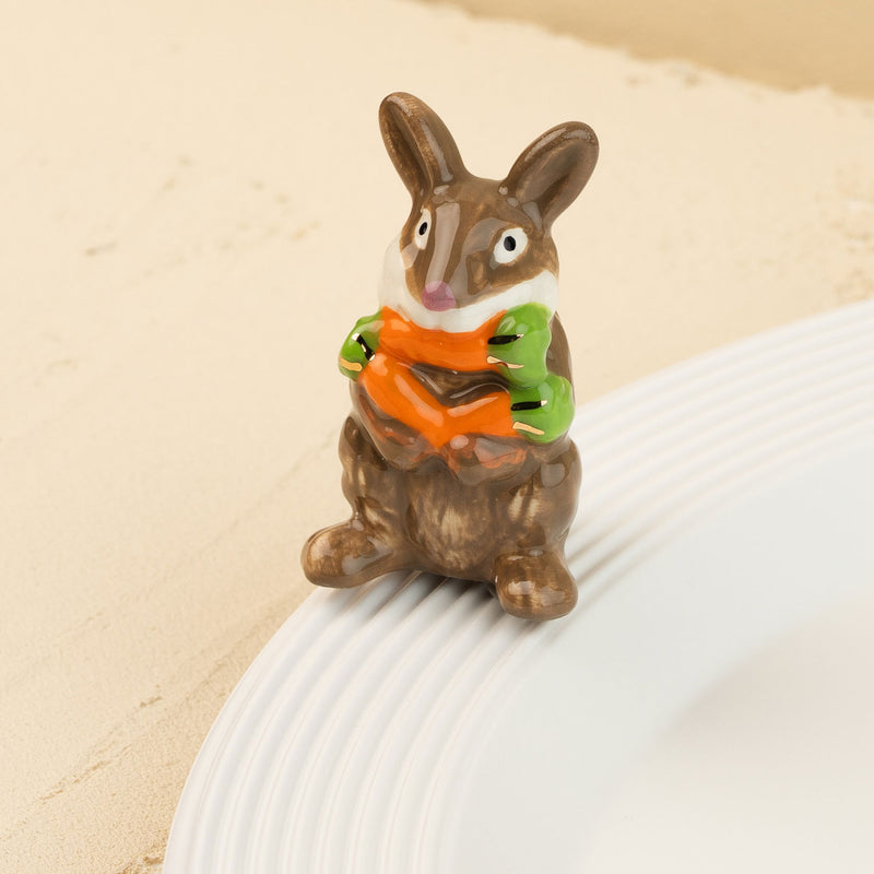 Decorative rabbit mini holding a carrot on a beige background