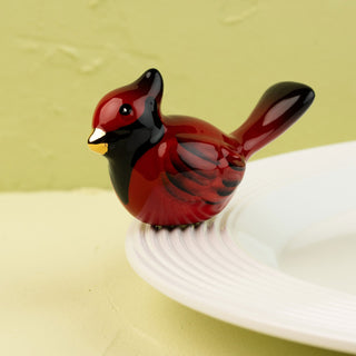 Red cardinal bird mini on a white plate with a yellow background