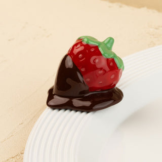 Strawberry-shaped mini covered in chocolate on a beige background