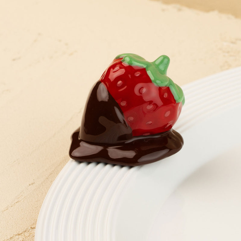 Strawberry-shaped mini covered in chocolate on a beige background