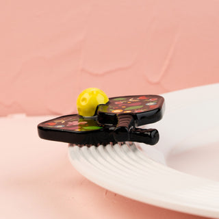 Decorative paddle mini with floral design on a white plate against a pink background