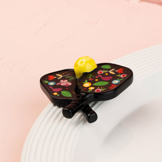 Decorative paddle mini with floral design on a white plate against a pink background