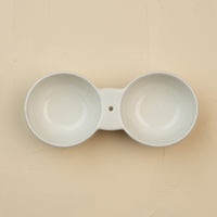 White ceramic double dipper on a beige background
