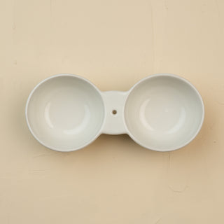 White ceramic double dipper on a beige background