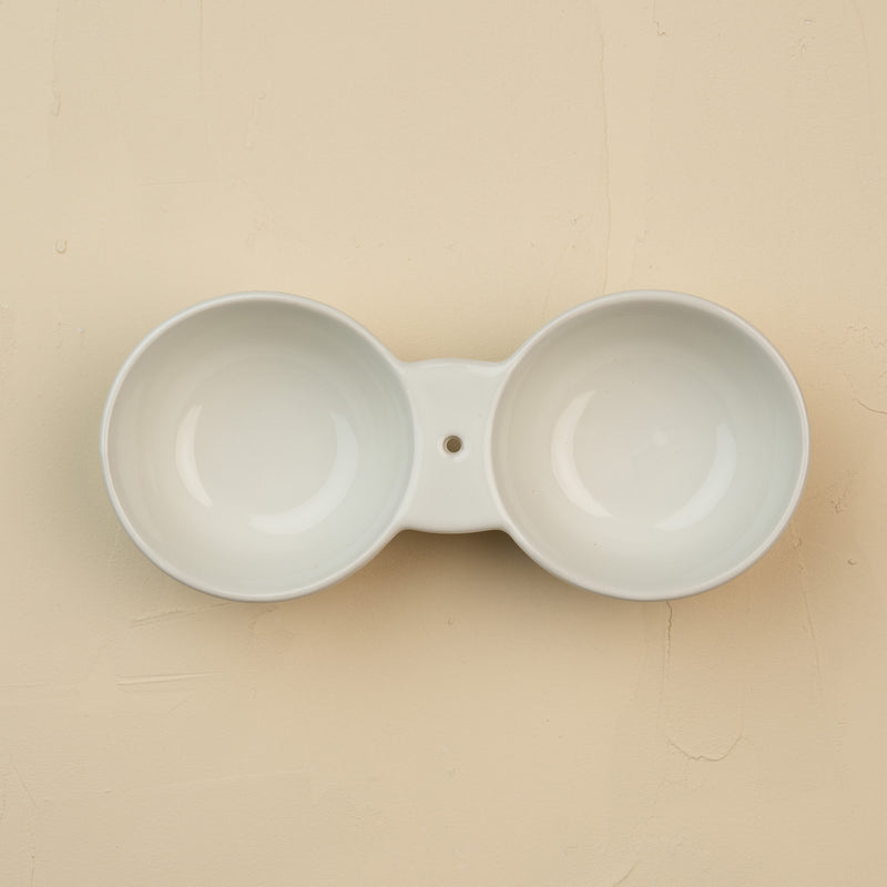 White ceramic double dipper on a beige background