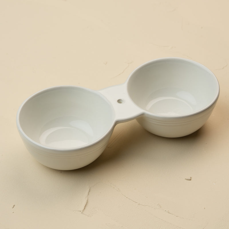 White ceramic double dipper on a beige background