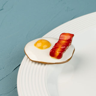 Fried egg and bacon mini on a white plate with a blue background