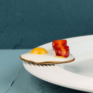 Fried egg and bacon mini on a white plate with a blue background