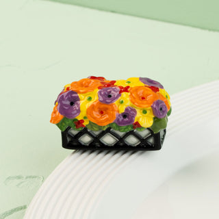 Colorful floral mini on a black flower  box on a white plate with a green background