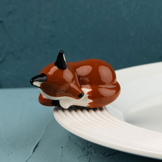 Sleeping fox mini on a white plate against a blue background