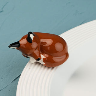 Sleeping fox mini on a white plate against a blue background