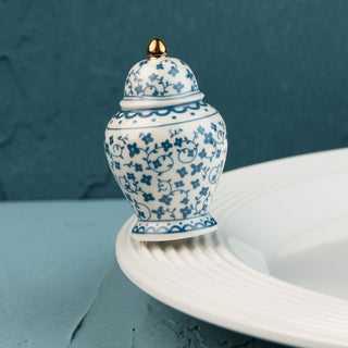 Blue and white ceramic jar mini with gold lid on a white surface against a teal background