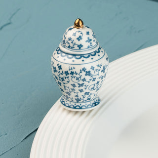 Blue and white ceramic jar mini with gold lid on a white surface against a teal background