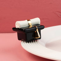 graduation hat mini on a white platter and pink background