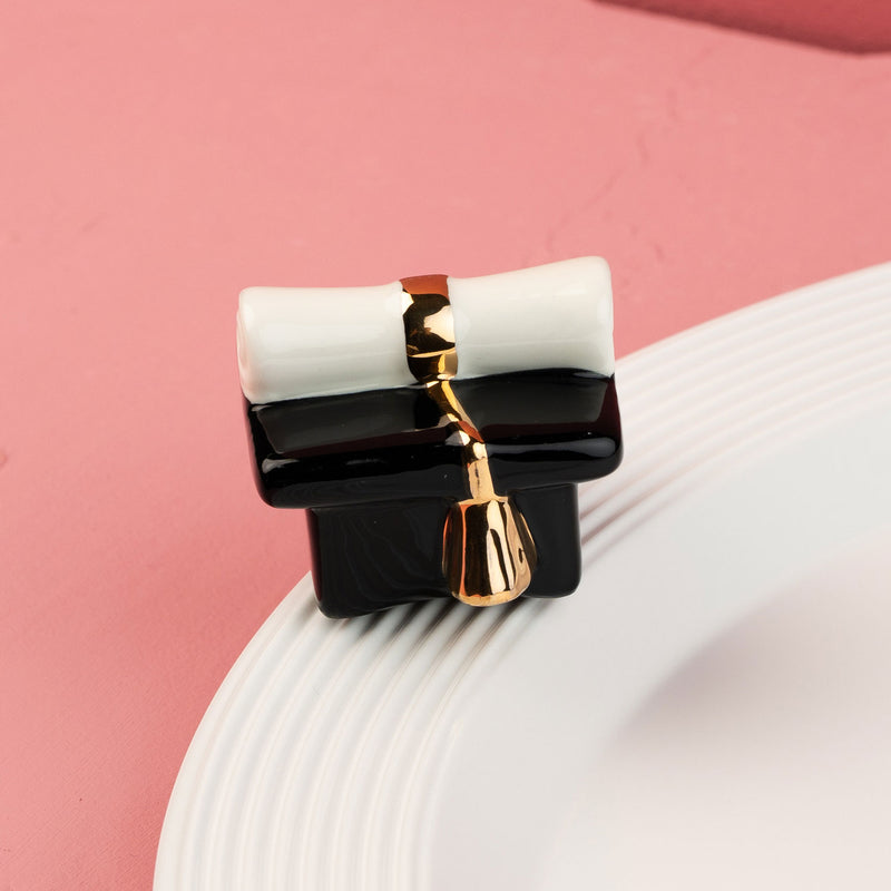 graduation hat mini on a white platter and pink background