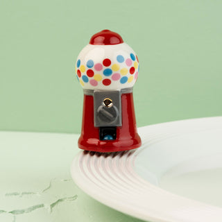 mini gumball machine with colorful polka dots on a light green background