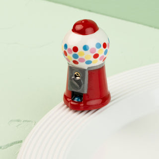 mini gumball machine with colorful polka dots on a light green background