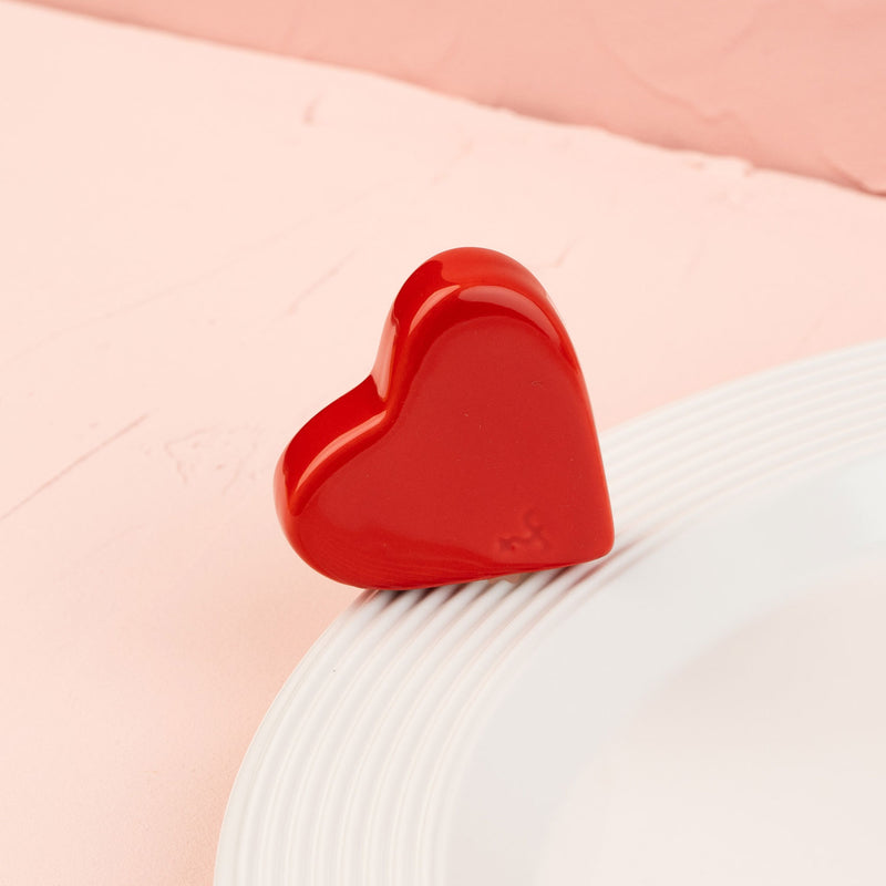 Red heart-shaped mini on a white platter with a pink background