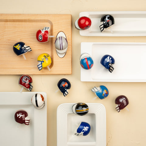 Collection of mini football helmets on a beige surface with wooden and white trays.