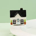 house mini with a green door and black roof on a white surface with a light green background