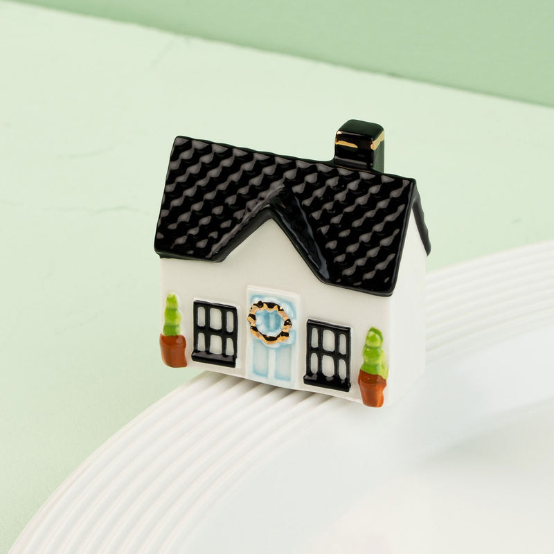 house mini with a green door and black roof on a white surface with a light green background