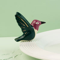 hummingbird mini on a white surface with a green background