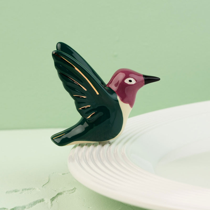 hummingbird mini on a white surface with a green background