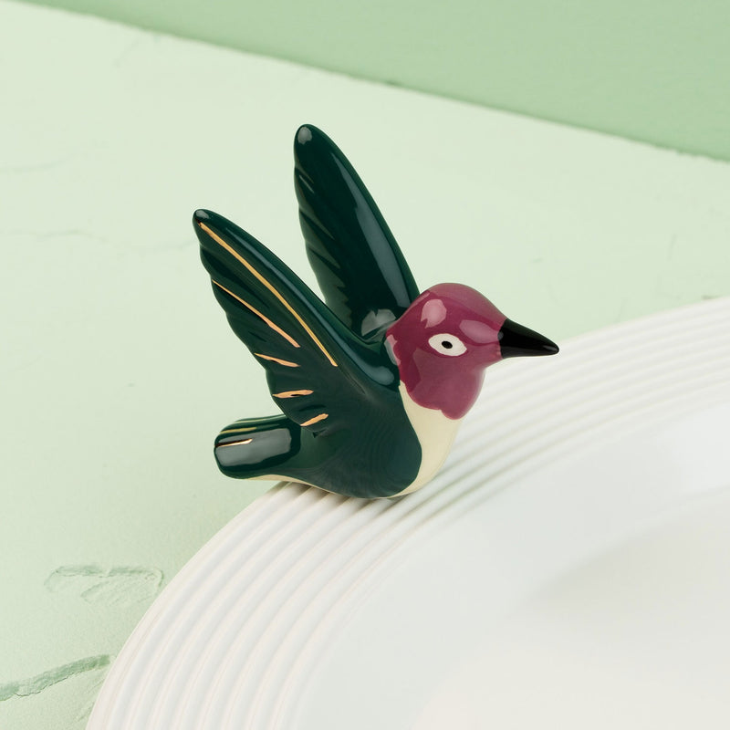 hummingbird mini on a white surface with a green background