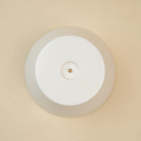A white round melamine riser with a central screw hole, designed to hold a platter. 