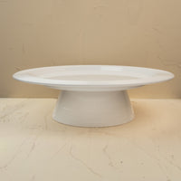 A white round melamine riser with a central screw hole, designed to hold a platter. 