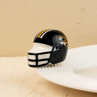 A small, decorative University of Missouri football helmet mini with a black and gold color scheme and the Missouri tiger logo on the side.